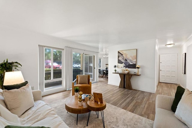 living room featuring an inviting chandelier, crown molding, and light hardwood / wood-style flooring