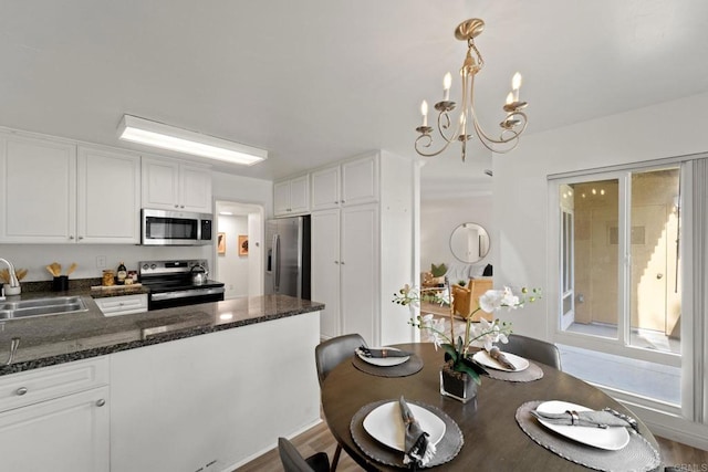 kitchen featuring white cabinets, sink, hardwood / wood-style flooring, decorative light fixtures, and stainless steel appliances