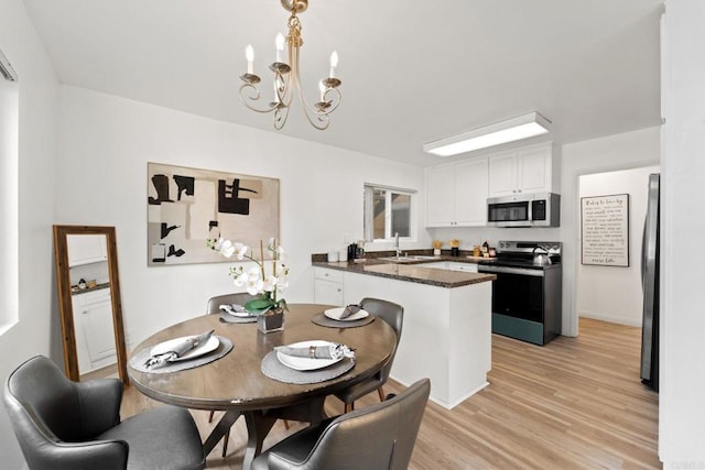 dining space featuring a chandelier, light wood-type flooring, and sink