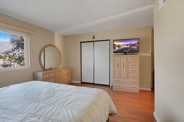 bedroom with a closet, a textured ceiling, and light wood-type flooring