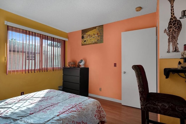 bedroom with light wood-type flooring and a textured ceiling