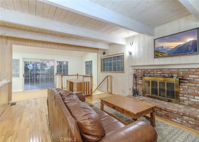 living room featuring light hardwood / wood-style flooring, wood ceiling, a fireplace, wood walls, and beamed ceiling