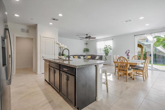 kitchen featuring sink, dark brown cabinetry, ceiling fan, stainless steel appliances, and a center island with sink