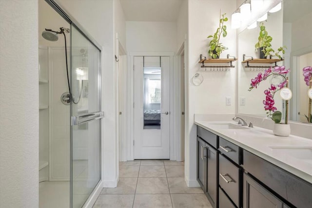 bathroom with a shower with door, vanity, and tile patterned floors