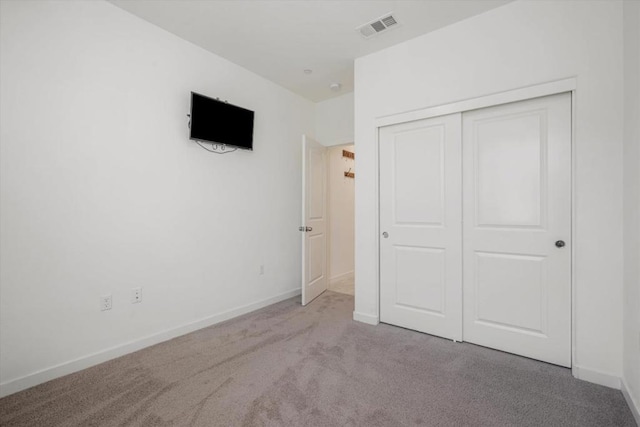 unfurnished bedroom featuring light colored carpet and a closet