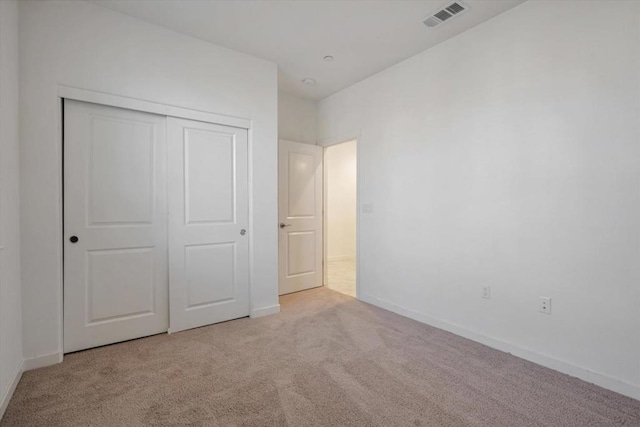 unfurnished bedroom featuring light carpet and a closet