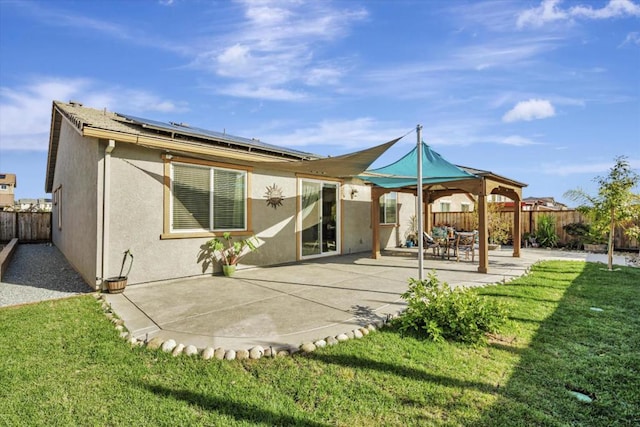 rear view of property with a patio, a gazebo, a lawn, and solar panels