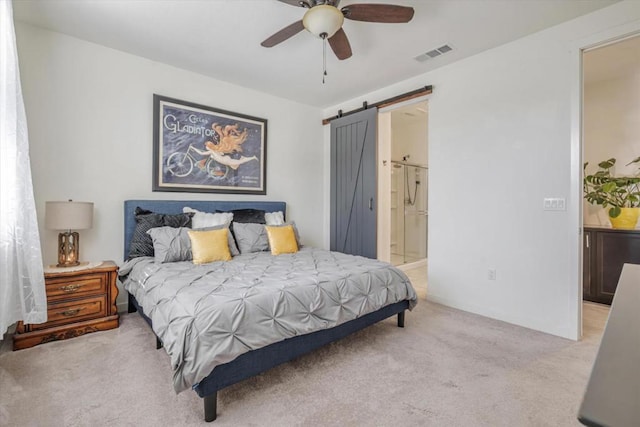 bedroom featuring ceiling fan, a barn door, light colored carpet, and ensuite bath