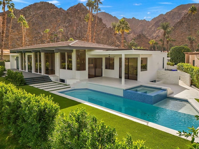 back of house featuring a pool with hot tub, a patio area, and a mountain view