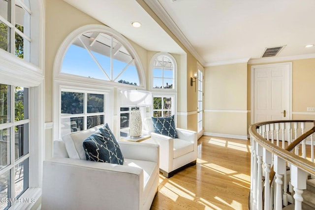 living room with light wood-type flooring, ornamental molding, and a high ceiling