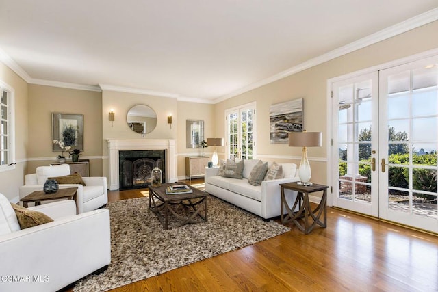 living room with a high end fireplace, french doors, hardwood / wood-style flooring, and ornamental molding