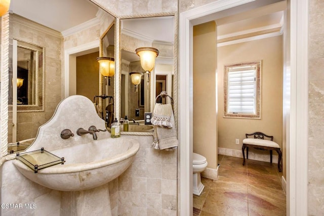 bathroom with sink, toilet, ornamental molding, and tile walls