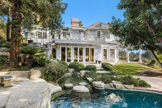 back of property with a balcony and french doors