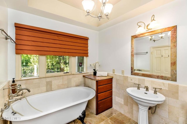 bathroom with a washtub, sink, tile walls, and an inviting chandelier