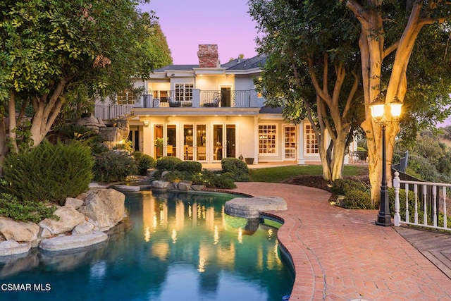 pool at dusk with a patio area and french doors