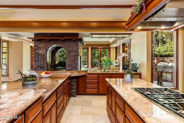 kitchen with premium range hood, light stone counters, sink, and stainless steel gas cooktop