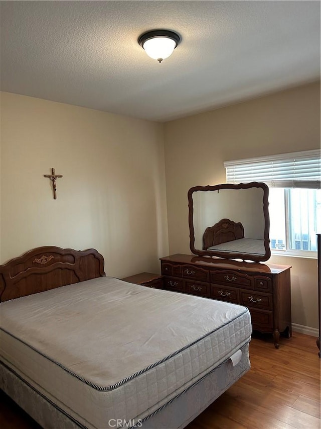 bedroom with a textured ceiling and light hardwood / wood-style flooring