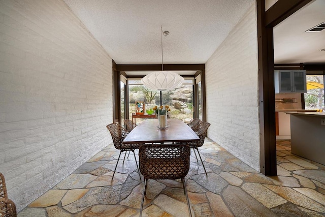 unfurnished dining area featuring a textured ceiling, brick wall, and vaulted ceiling