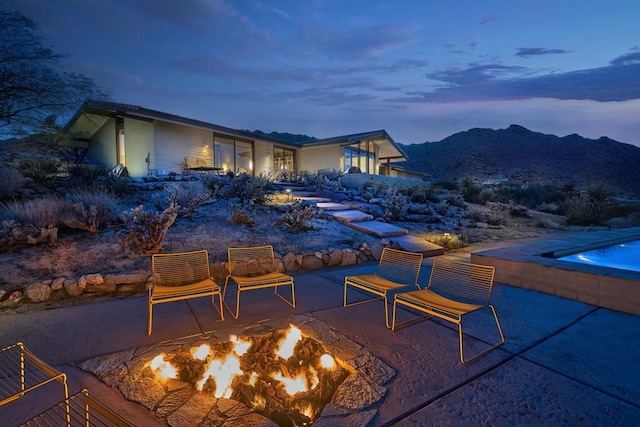 patio terrace at dusk with a mountain view and an outdoor fire pit