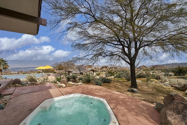 view of pool featuring a mountain view, a patio, and a hot tub