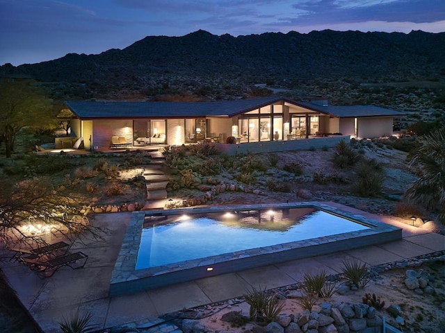 pool at dusk featuring a mountain view and a patio area