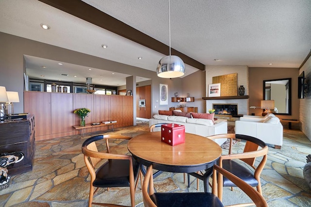 dining area featuring a textured ceiling, a fireplace, and vaulted ceiling