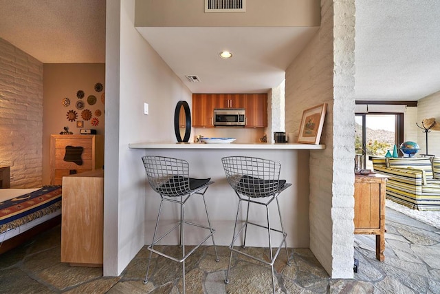 kitchen featuring kitchen peninsula, a textured ceiling, and a breakfast bar area