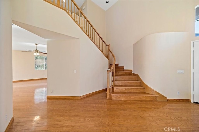 stairway featuring hardwood / wood-style floors, ceiling fan, and high vaulted ceiling