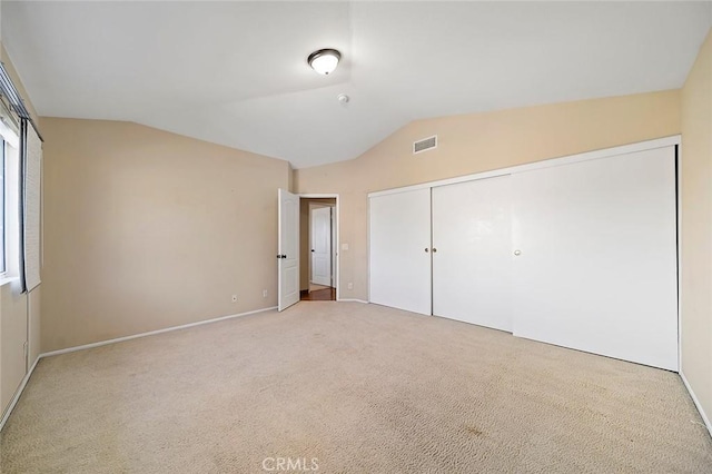 unfurnished bedroom with lofted ceiling, carpet floors, and a closet