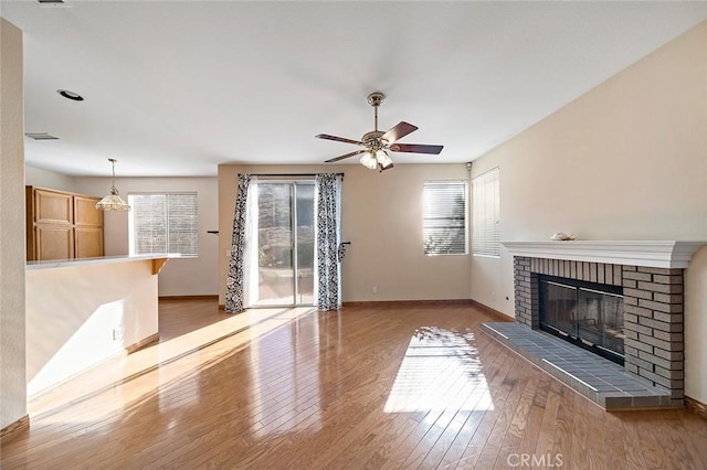 unfurnished living room featuring a fireplace, hardwood / wood-style flooring, and ceiling fan