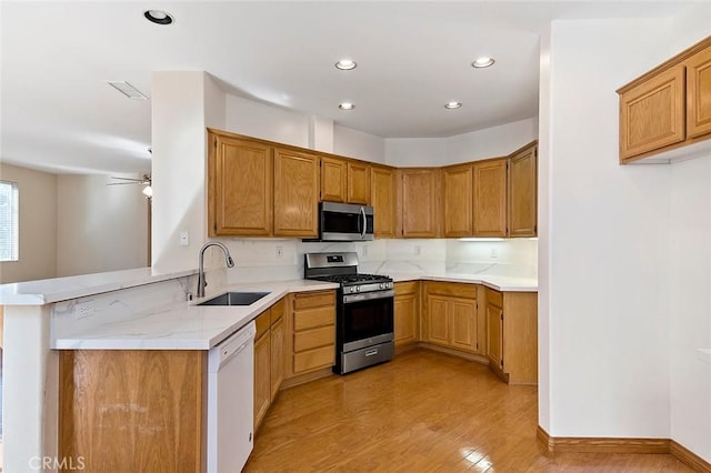 kitchen featuring sink, ceiling fan, appliances with stainless steel finishes, light hardwood / wood-style floors, and kitchen peninsula