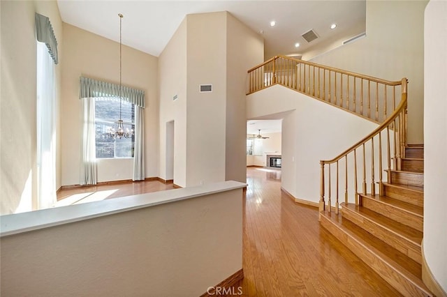 interior space with decorative light fixtures, a high ceiling, ceiling fan with notable chandelier, and hardwood / wood-style flooring