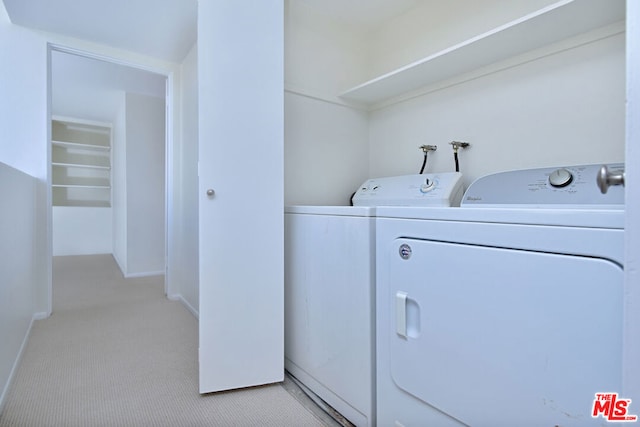 laundry area featuring washing machine and clothes dryer and light carpet