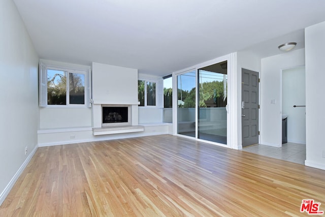 unfurnished living room with light hardwood / wood-style flooring and a wealth of natural light