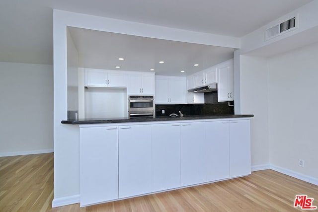 kitchen featuring decorative backsplash, double oven, sink, light hardwood / wood-style flooring, and white cabinetry