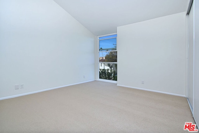 empty room with light colored carpet and vaulted ceiling