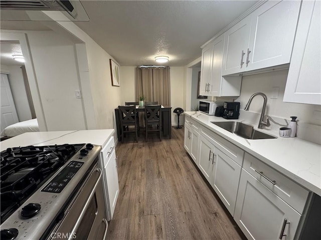 kitchen featuring stainless steel gas stove, white cabinetry, sink, and dark hardwood / wood-style floors