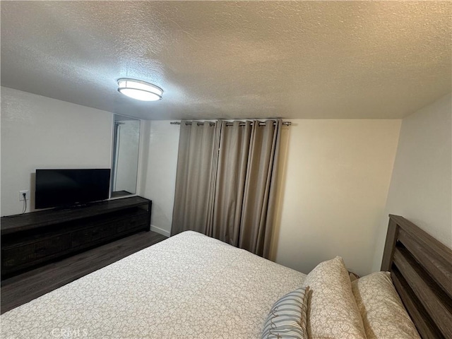 bedroom featuring a textured ceiling and dark wood-type flooring