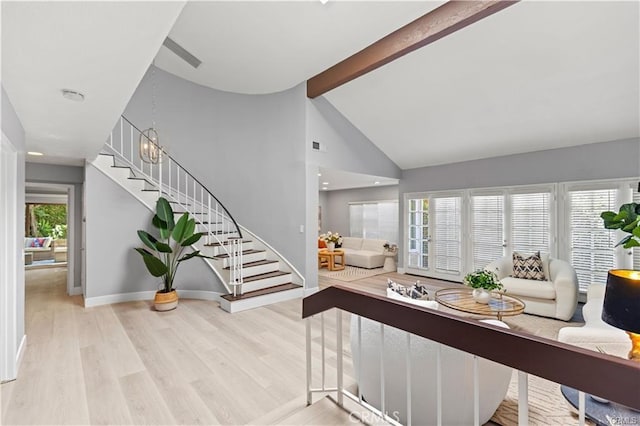 foyer entrance featuring a chandelier, beamed ceiling, a healthy amount of sunlight, and light hardwood / wood-style floors