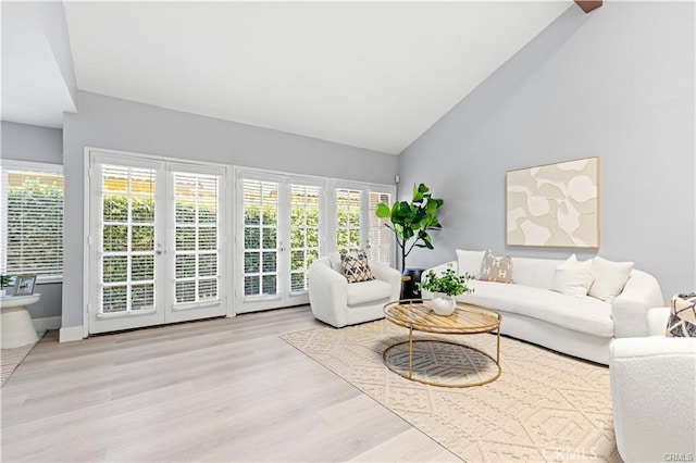 living room with french doors, light hardwood / wood-style floors, and high vaulted ceiling