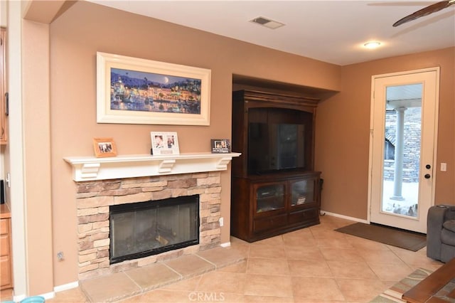 living room featuring a fireplace, ceiling fan, and light tile patterned flooring