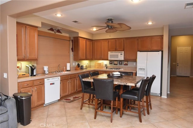 kitchen with ceiling fan, a breakfast bar, light tile patterned floors, and white appliances