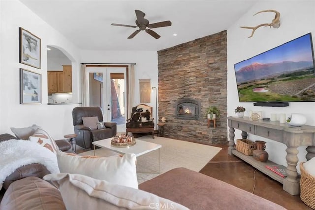 living room featuring ceiling fan, a wood stove, and french doors