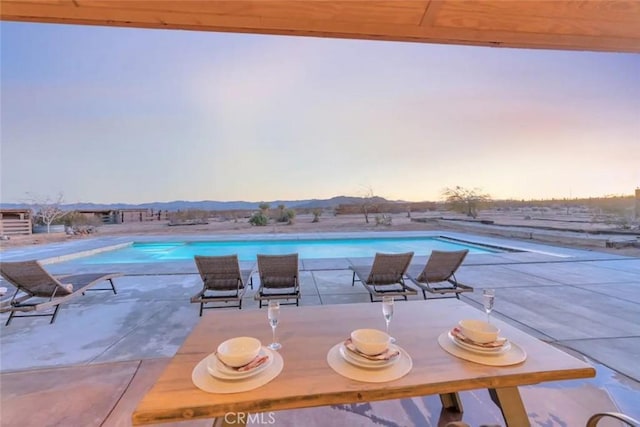 pool at dusk with a patio area