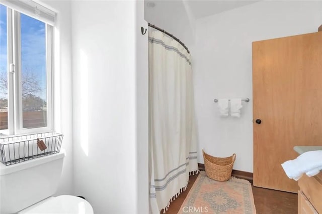 bathroom with a shower with curtain, toilet, and plenty of natural light