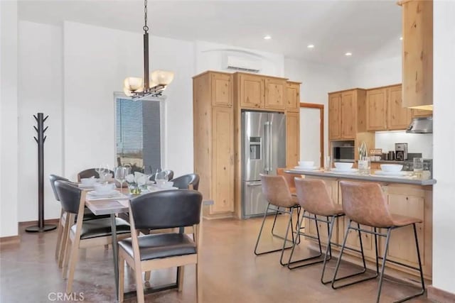 kitchen with kitchen peninsula, stainless steel refrigerator with ice dispenser, pendant lighting, an AC wall unit, and a notable chandelier