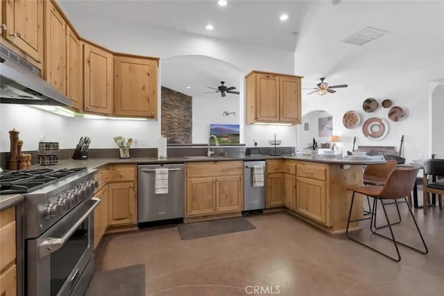 kitchen with a breakfast bar, sink, range hood, appliances with stainless steel finishes, and kitchen peninsula