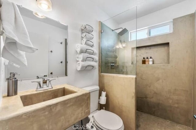 bathroom featuring a tile shower, toilet, and sink