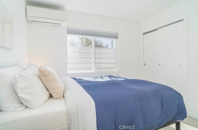 bedroom with an AC wall unit and a closet