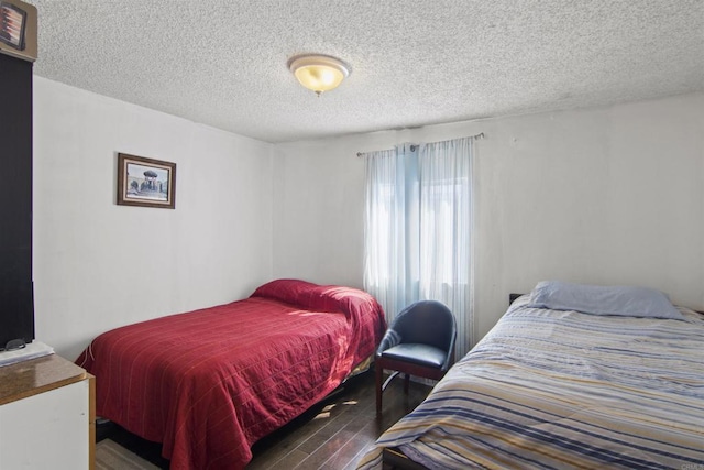 bedroom featuring a textured ceiling and dark hardwood / wood-style floors